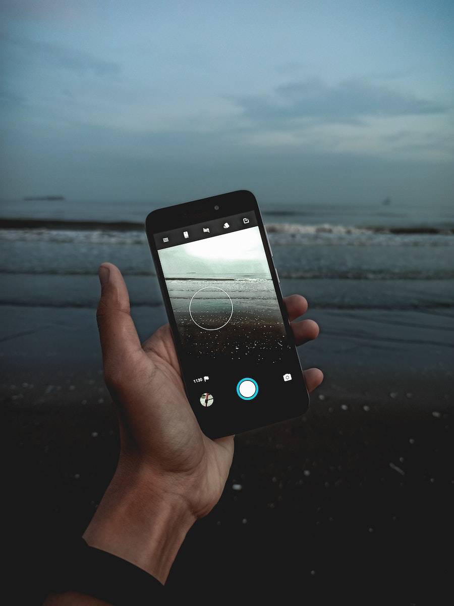 Hand Holding Cellphone Filming Evening Ocean